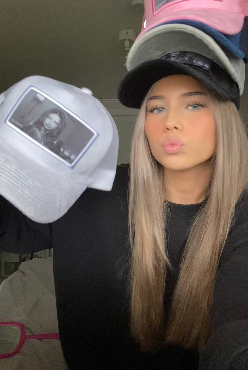 Woman showing various caps with images of a model on them.