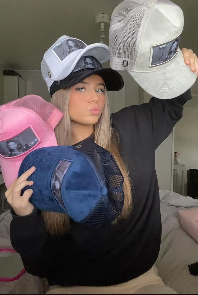 Woman showcasing four different colored hats featuring Adriana Lima's imagery.