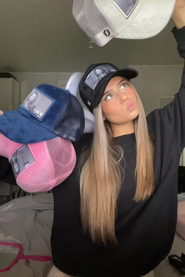 Woman showcasing various stylish caps in different colors, including white, black, blue, and pink.