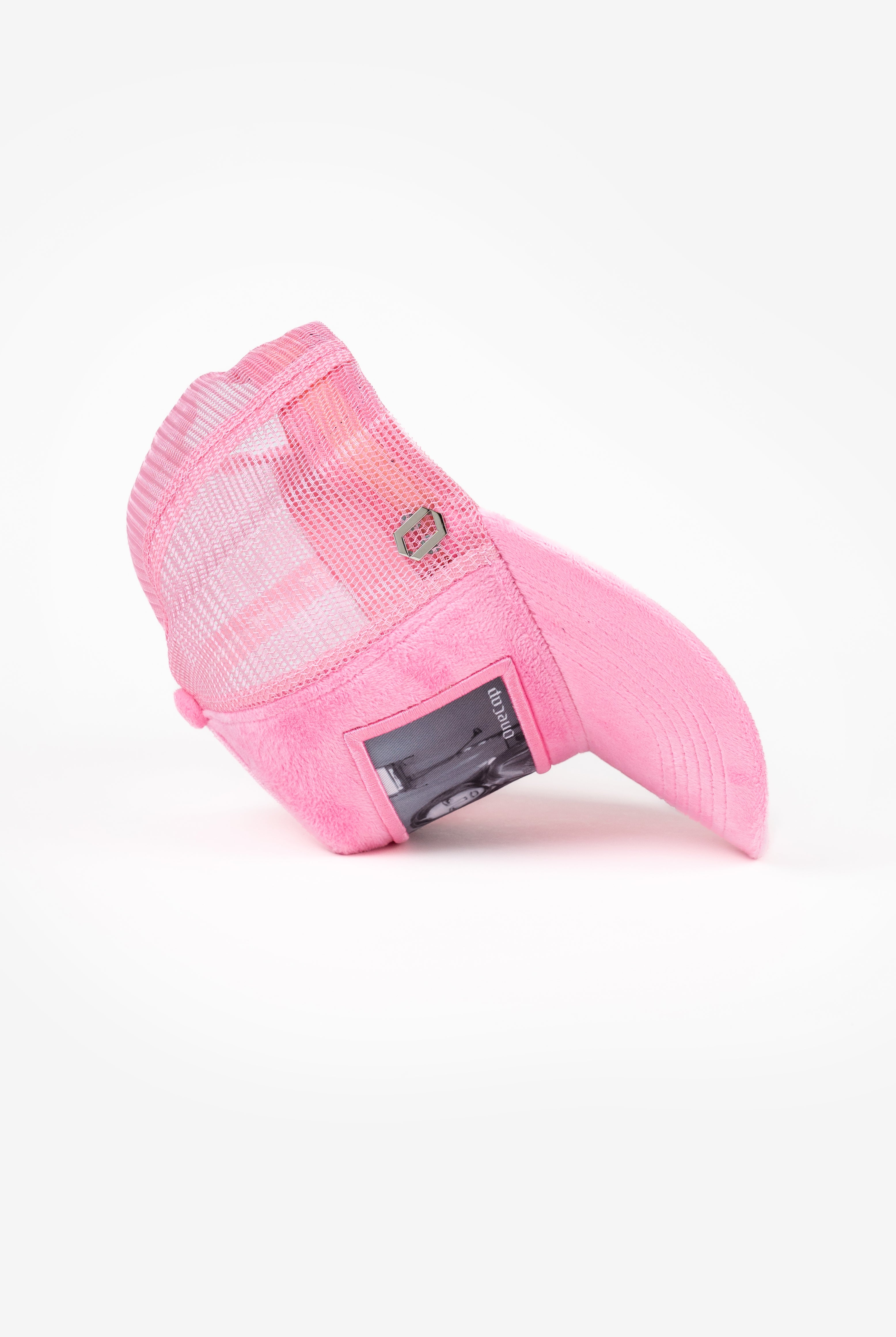 Pink mesh baseball cap laid on its side, featuring a small window with a picture inserted.