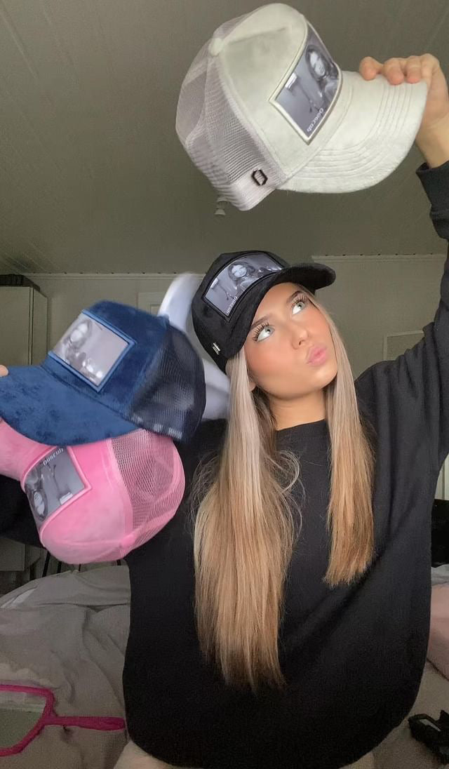 Woman showcasing various stylish caps in different colors, including white, black, blue, and pink.